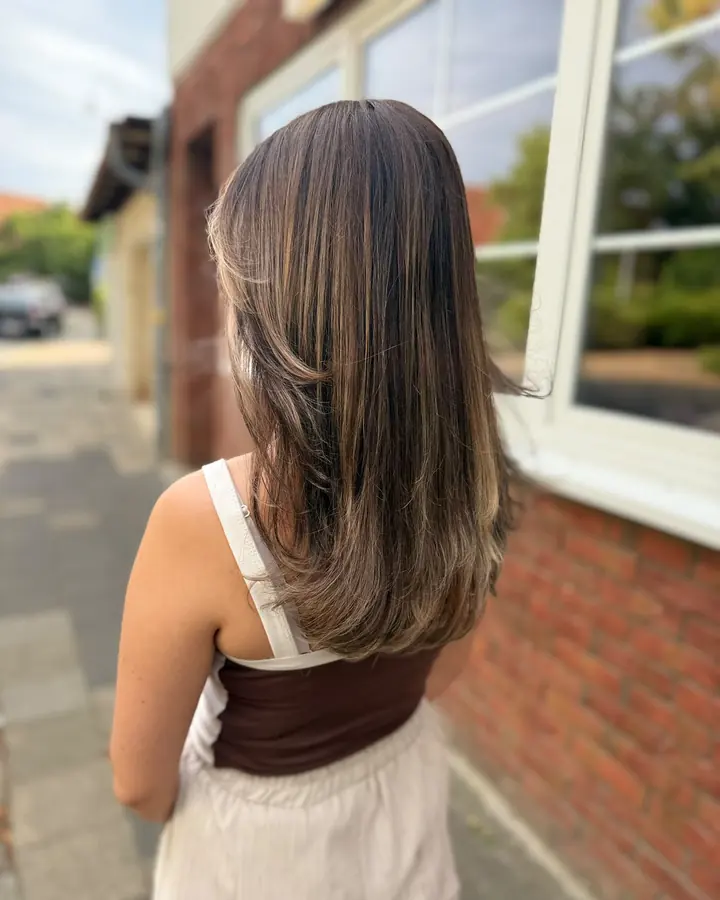 Lange, braune Haare mit hellen Balayage-Strähnen, von hinten